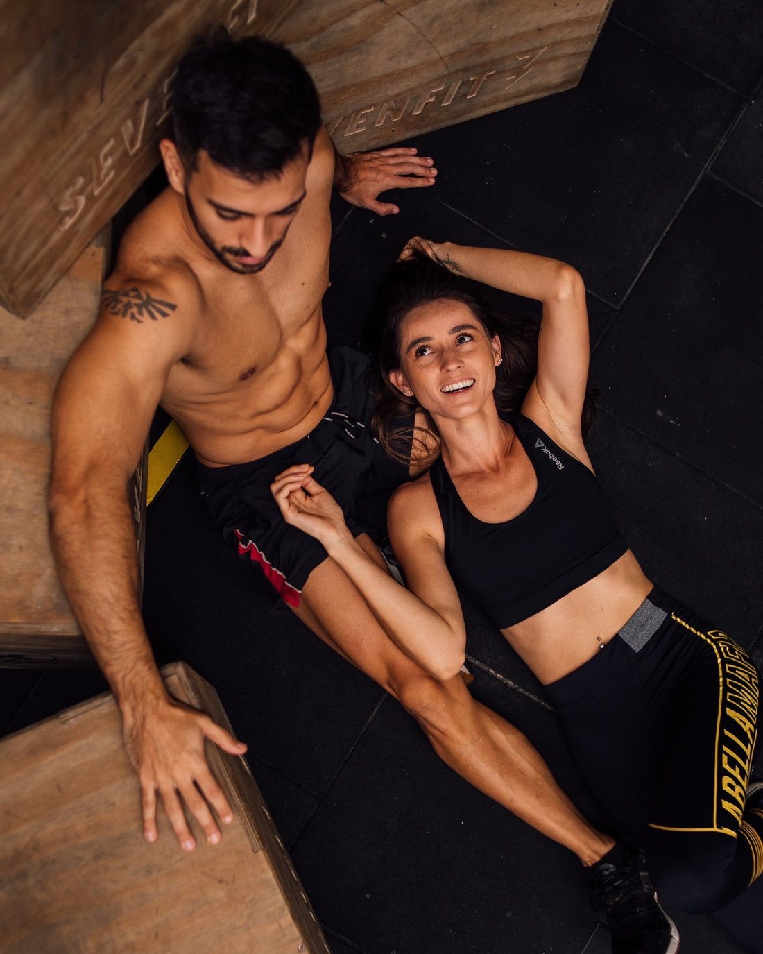 Two people lying on a gym platform, laughing