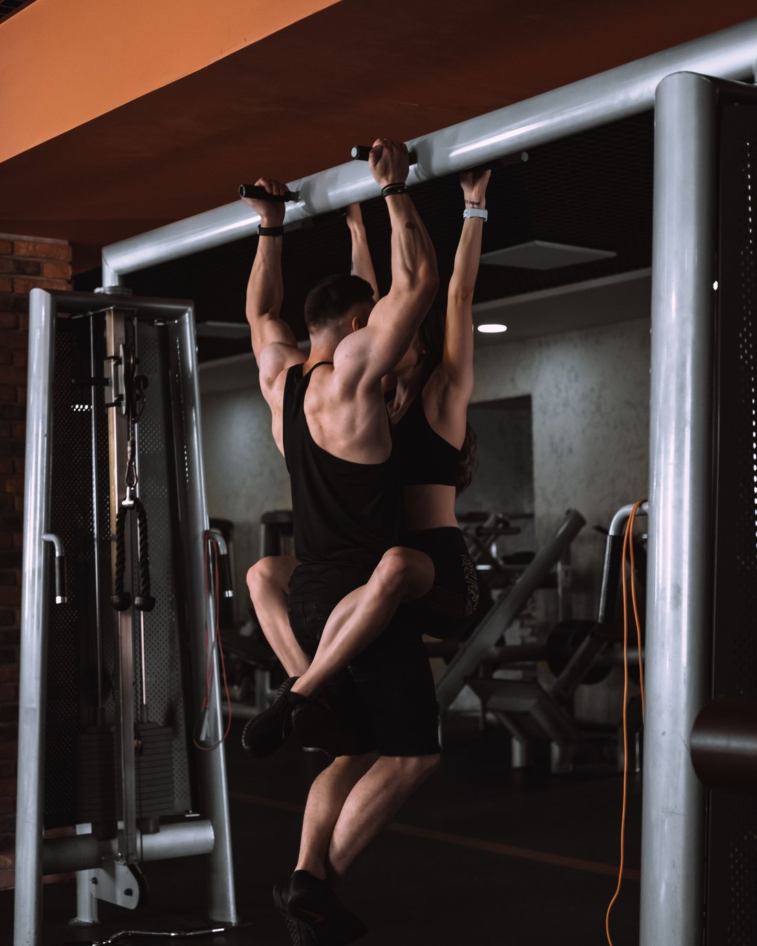 Two people on the pull-up bars of their own gym
